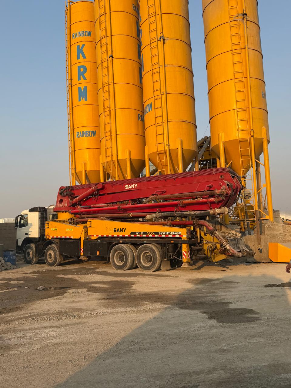 Concrete pump truck positioned beside Karachi Ready Mix silos
